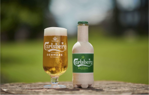 Carlsberg glass with beer and a Carlsberg paper bottle on a wooden table, nature in the background