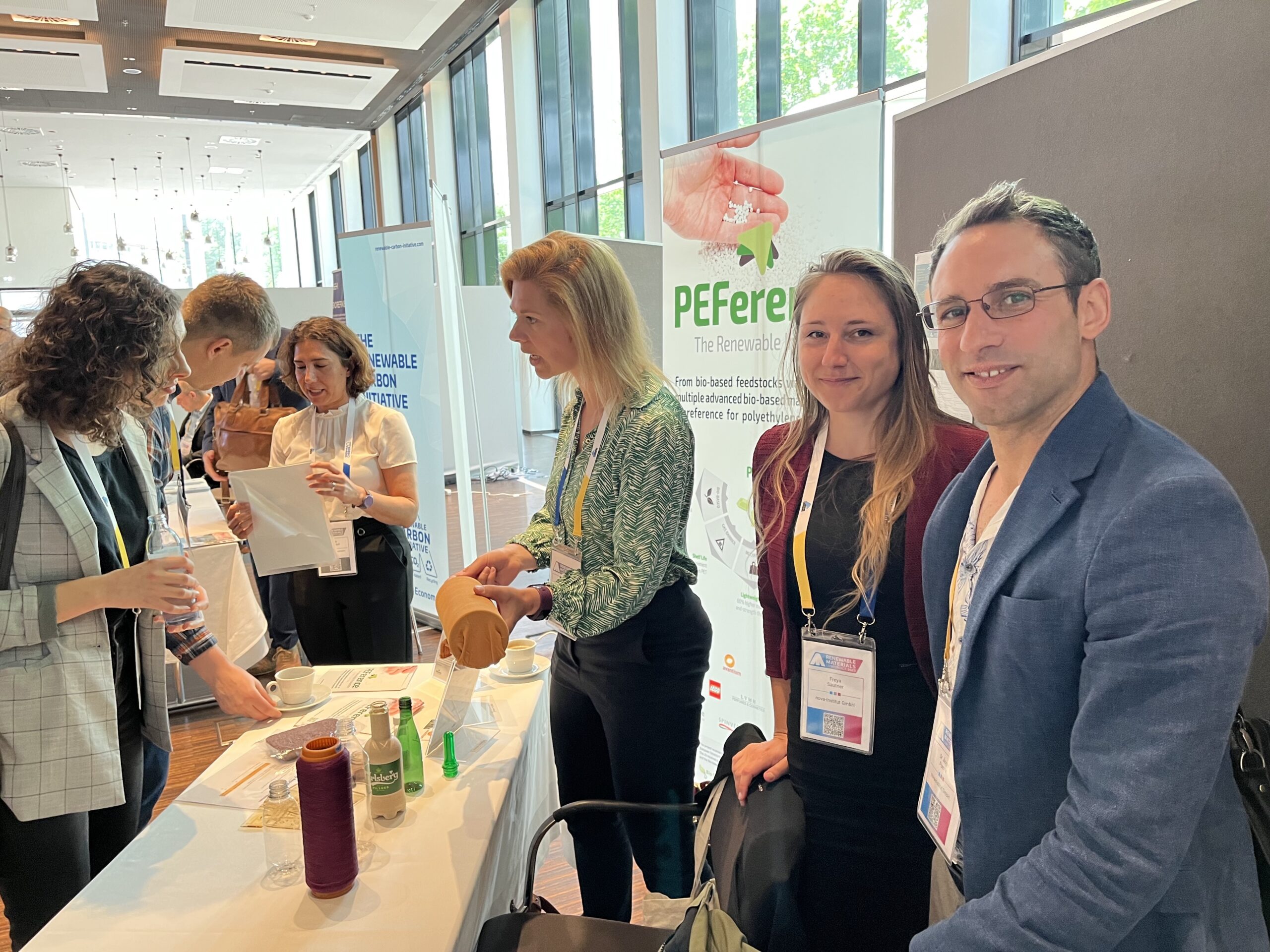 Busy PEFerence booth at the Renewable Materials Conference 2023, Ángel Puente, Freya Sautner, Ingrid Goumans and Sheila Khodadadi behind the booth explaining stuff to visitors